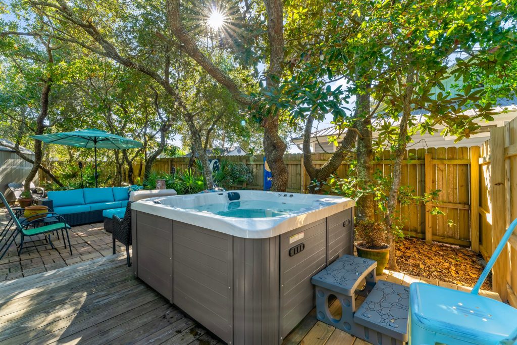 Home Relaxing private hot tub on the outdoor wooden deck surrounded by trees at Barefoot Paradise in Panama City Beach.
